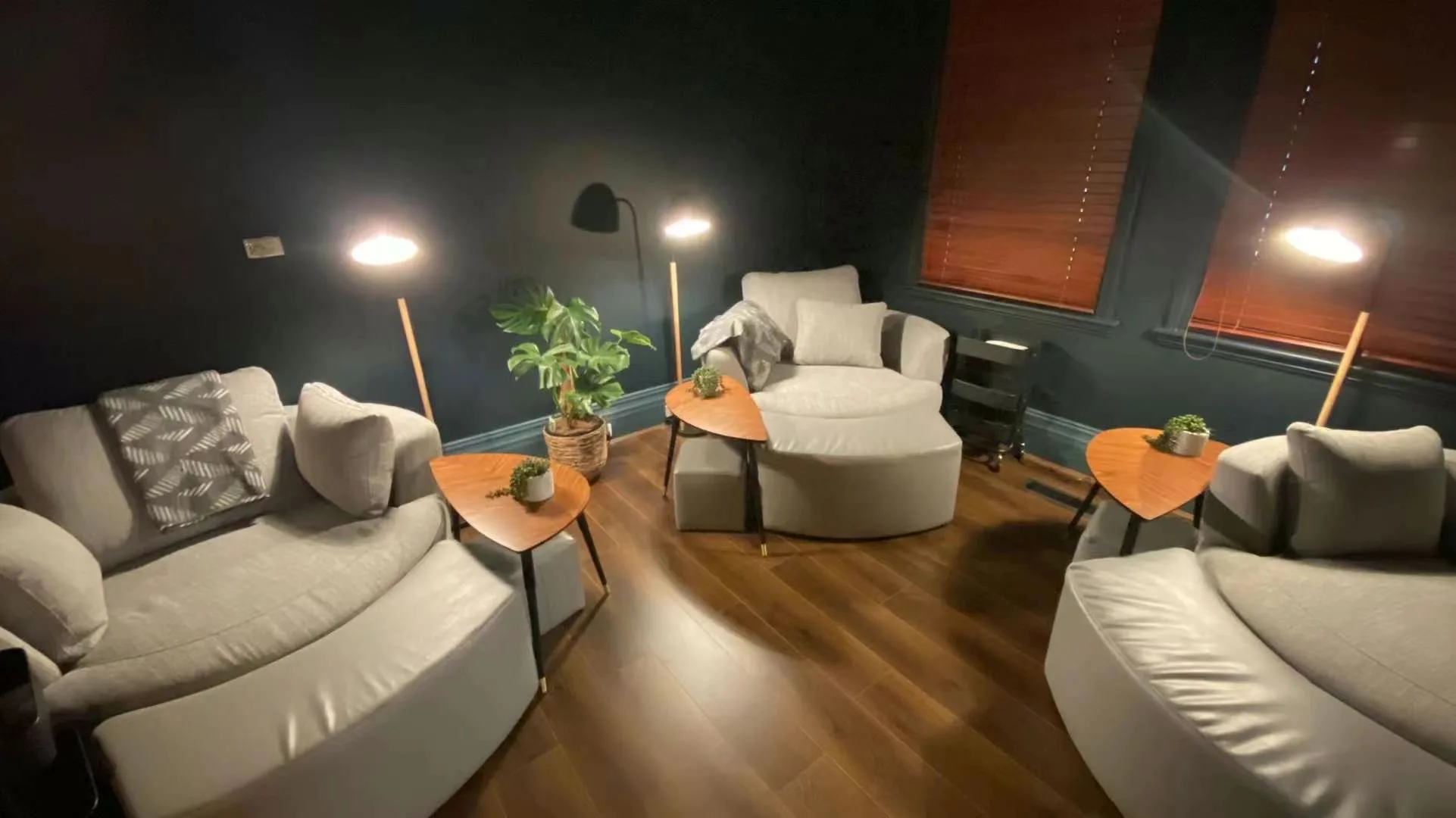 Relaxation lounge with round cream tub chairs, floor lamps, monstera and timber blinds
