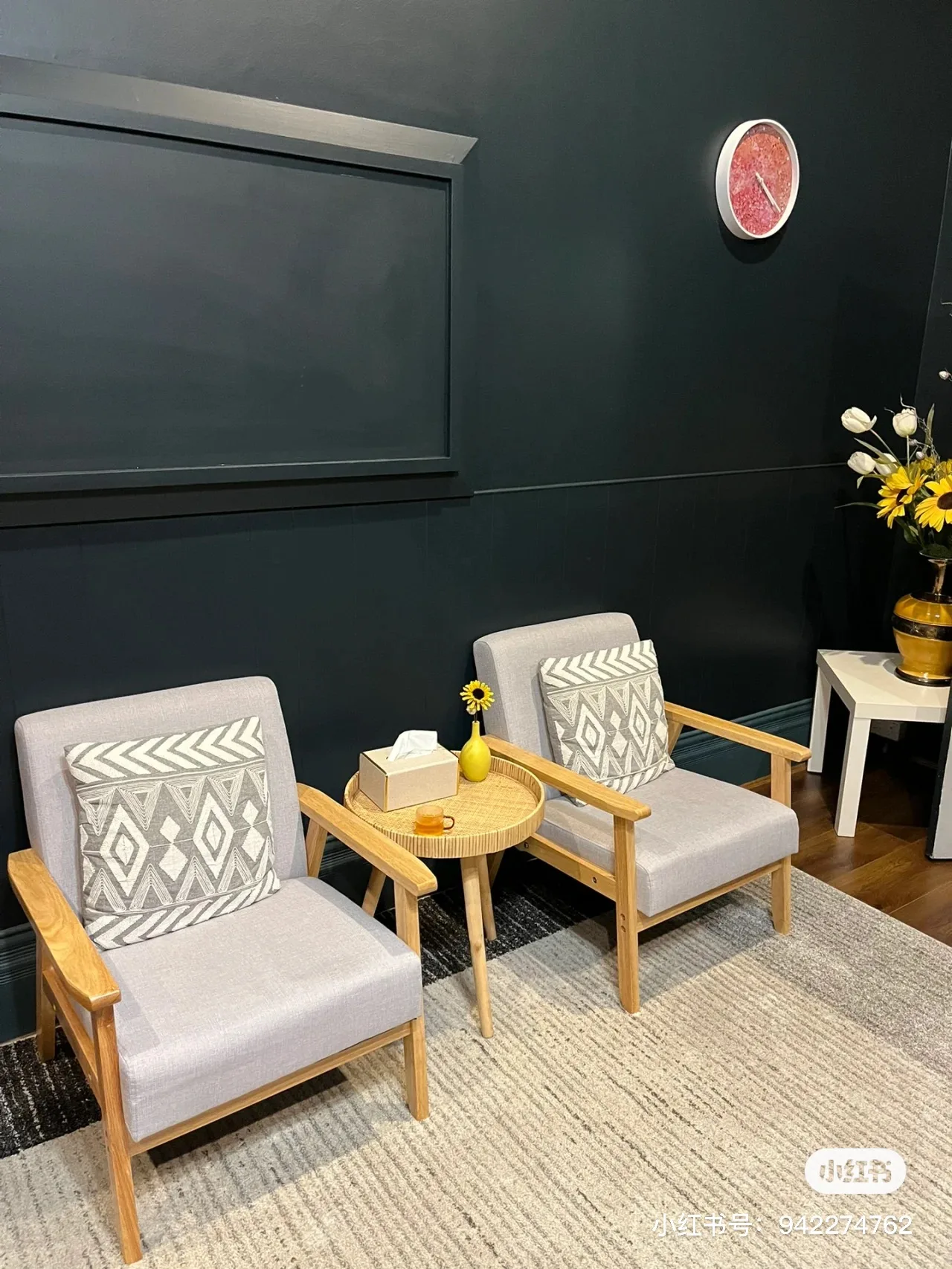 Waiting nook with two grey armchairs and a rattan tray table with sunflowers