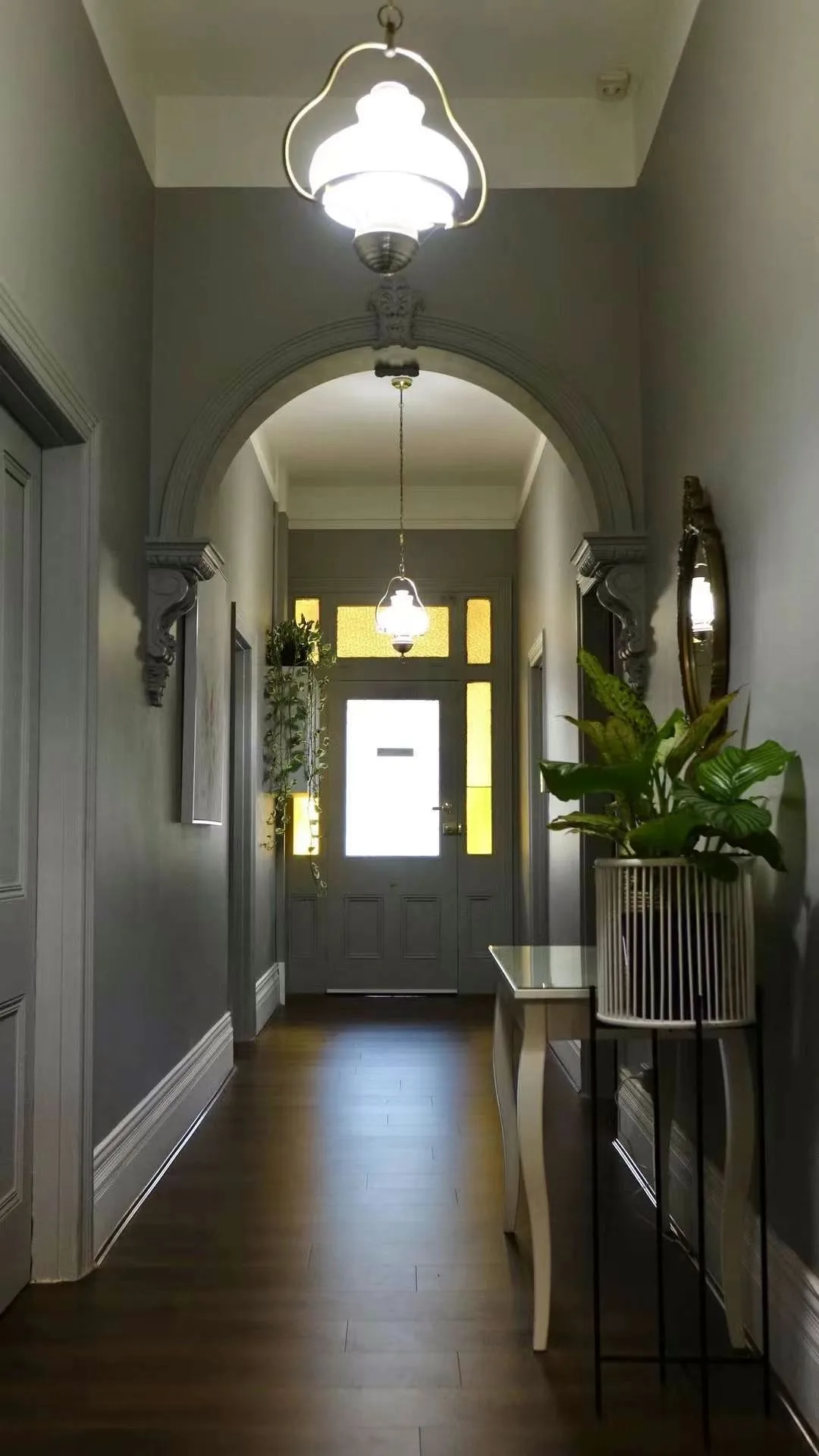 Heritage entrance hall: round-topped plaster arch with pendant lantern and stained-glass front door