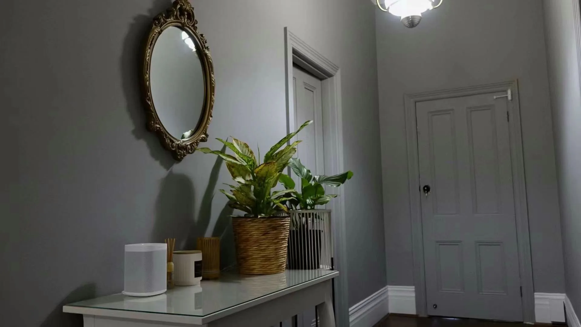 Entry vignette: ornate gold oval mirror, console with diffuser and candles, potted plant