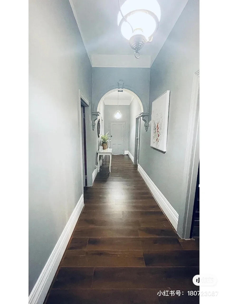 Grey heritage corridor with a round-topped arch and a console receding to a lit doorway